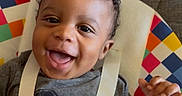 Noa joined the competition — help win amazing prizes! baby, child, smiling, curly_hair, mickey_mouse, shirt, baby_chair, colorful, happy, face, hand, playing, seated, indoors, cute, infant, young, person, clothing, expression