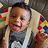 baby, child, smiling, curly_hair, mickey_mouse, shirt, baby_chair, colorful, happy, face, hand, playing, seated, indoors, cute, infant, young, person, clothing, expression