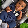 baby, child, infant, car_seat, blue_outfit, white_socks, curly_hair, brown_skin, indoors, seat_belt, gray_fabric, green_grass, cute, portrait, looking_up, hands, expression, comfortable, casual_clothing, young