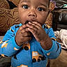 Rakai joined the competition — help win amazing prizes! blanket, blue_onesie, brown_furniture, child, chocolate, cookie, couch, cozy, curly_hair, cute, face, focused, hands, home, indoor, portrait, sitting, snack, toddler, young_child