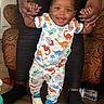 baby, child, clothing, couch, dinosaur_pajamas, floor, footwear, furniture, hands, happy, home, indoor, nails, person, smile, support, toddler, walking, water_bottle, wooden_floor