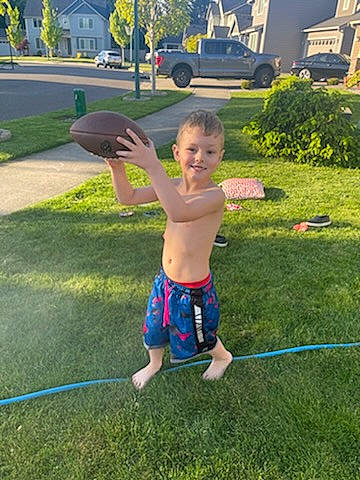 Alaric is registered to the contest to win money with this photo: balance, barefoot, child, fun, grass, grass_family, joy, lawn, leisure, people_in_nature, person, plant, public_space, shorts, smile, summer, swimwear, tire, toddler, toy