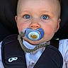 baby, blue_eyes, pacifier, car_seat, child, infant, clothing, cute, close_up, face, head, seatbelt, straps, white_shirt, animal_print, adorable, young_child, person, indoors, portrait