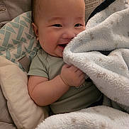 Zaire joined the competition — help win amazing prizes! baby, infant, child, smiling, portrait, blanket, cuddling, pillow, bed, indoor, cozy, happy, face, eyes, hands, clothing, seated, soft, warm_lighting, photography
