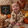 Zaire is registered to the contest to win money with this photo: baby, infant, child, smiling, sitting, portrait, autumn, fall, pumpkins, leaves, teddy_bear, blanket, cozy, indoor, seasonal_decor, letter_board, six_months, onesie, happy, photography