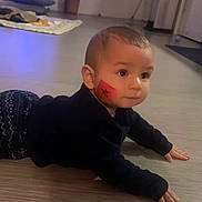 Nael a rejoint le concours — aidez-le/la à gagner de superbes lots ! baby, black_clothing, cheek_mark, child, crawling, cute, expression, face_paint, floor, flooring, hands, head, indoor, infant, patterned_pants, person, skin, wide_eyes, wooden_floor, young_child