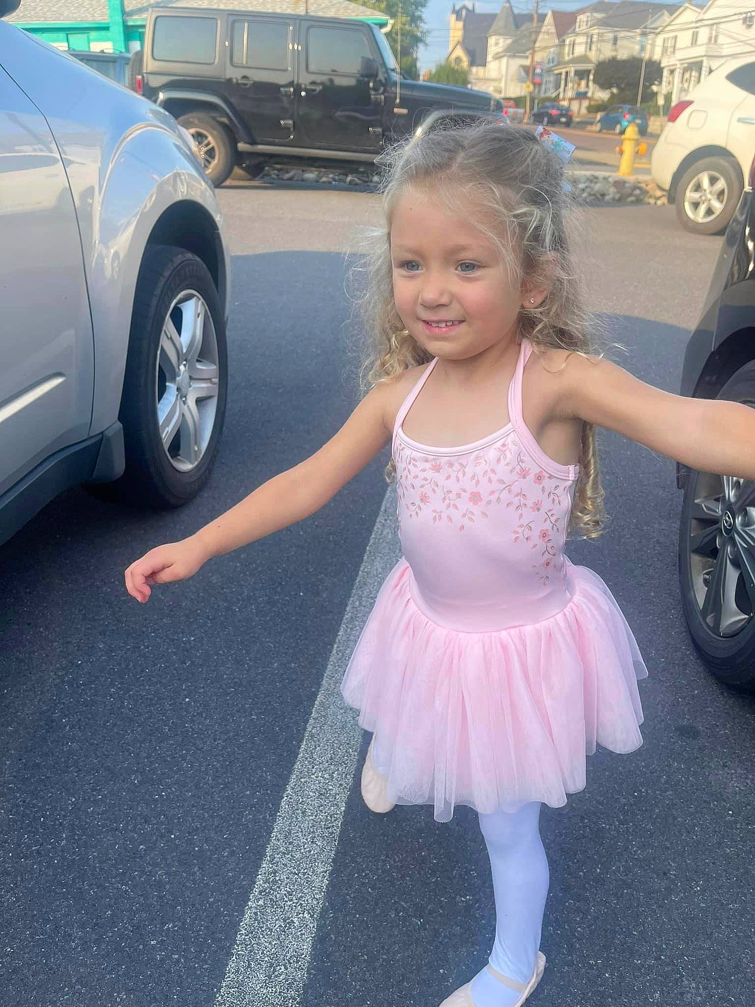 Arayah is registered to the contest to win money with this photo: asphalt, automotive_design, automotive_exterior, automotive_tire, ballet_tutu, beauty, car, fun, happy, joy, motor_vehicle, parking, person, pink, road, smile, snapshot, tire, toddler, vehicle