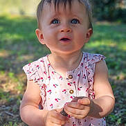 Albane a rejoint le concours — aidez-le/la à gagner de superbes lots ! toddler, child, outdoor, grass, dress, patterned_clothing, holding, stick, curious, blue_eyes, sunlight, nature, young_child, sitting, expression, portrait, summer, daylight, cute, innocence