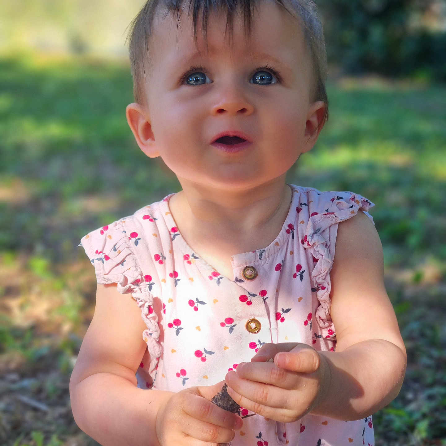 Albane a rejoint le concours — aidez-le/la à gagner de superbes lots ! blue_eyes, child, curious, cute, daylight, dress, expression, grass, holding, innocence, nature, outdoor, patterned_clothing, portrait, sitting, stick, summer, sunlight, toddler, young_child