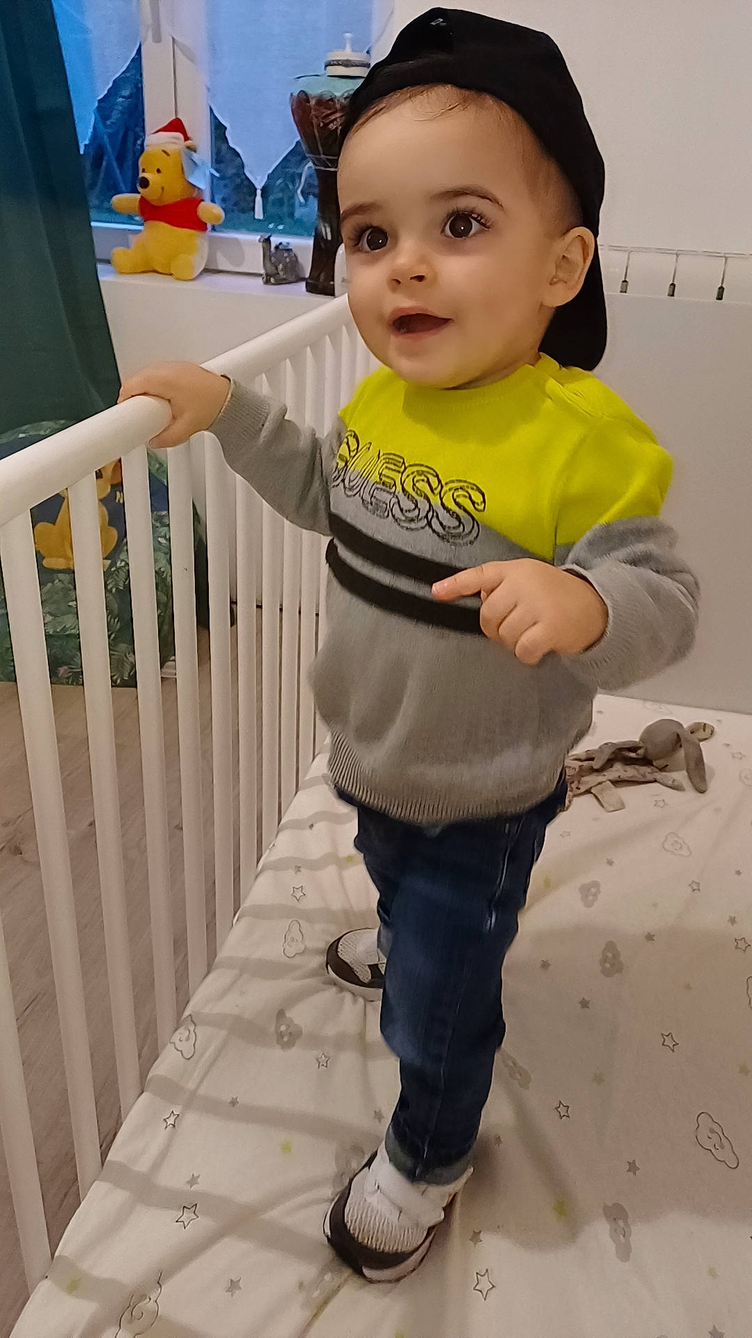 Nahïm participe au concours pour gagner de l'argent avec cette photo : baby, baby_toddler_clothing, blue, cap, cheek, child, face, flooring, fun, happy, person, play, room, sitting, skin, sleeve, t_shirt, toddler, vacation, white