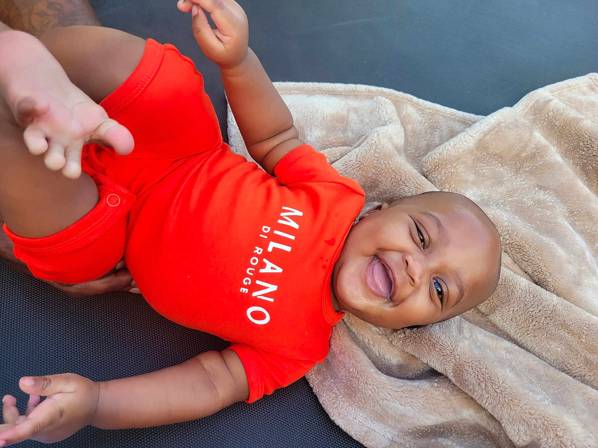 Kaizen joined the competition — help win amazing prizes! baby, smiling, red_onesie, blanket, happy, child, infant, face, skin, hand, foot, lying_down, soft_texture, clothing, cute, portrait, relaxed, indoors, baby_girl, baby_boy
