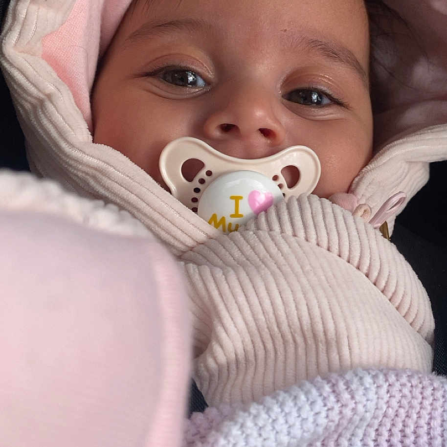 Anaïs is registered to the contest to win money with this photo: apparel, baby, blanket, bundle, child, closeup, cozy, cute, face, hood, infant, knitted, pacifier, person, pink, portrait, sleepy, snug, soft, warm