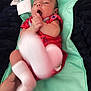 Joseph is registered to the contest to win money with this photo: baby, infant, red_clothing, white_socks, mint_green_mat, hand, foot, blur, sleepy, lying_down, indoor, person, newborn, cute, soft_texture, fabric, skin, portrait, baby_gesture, resting