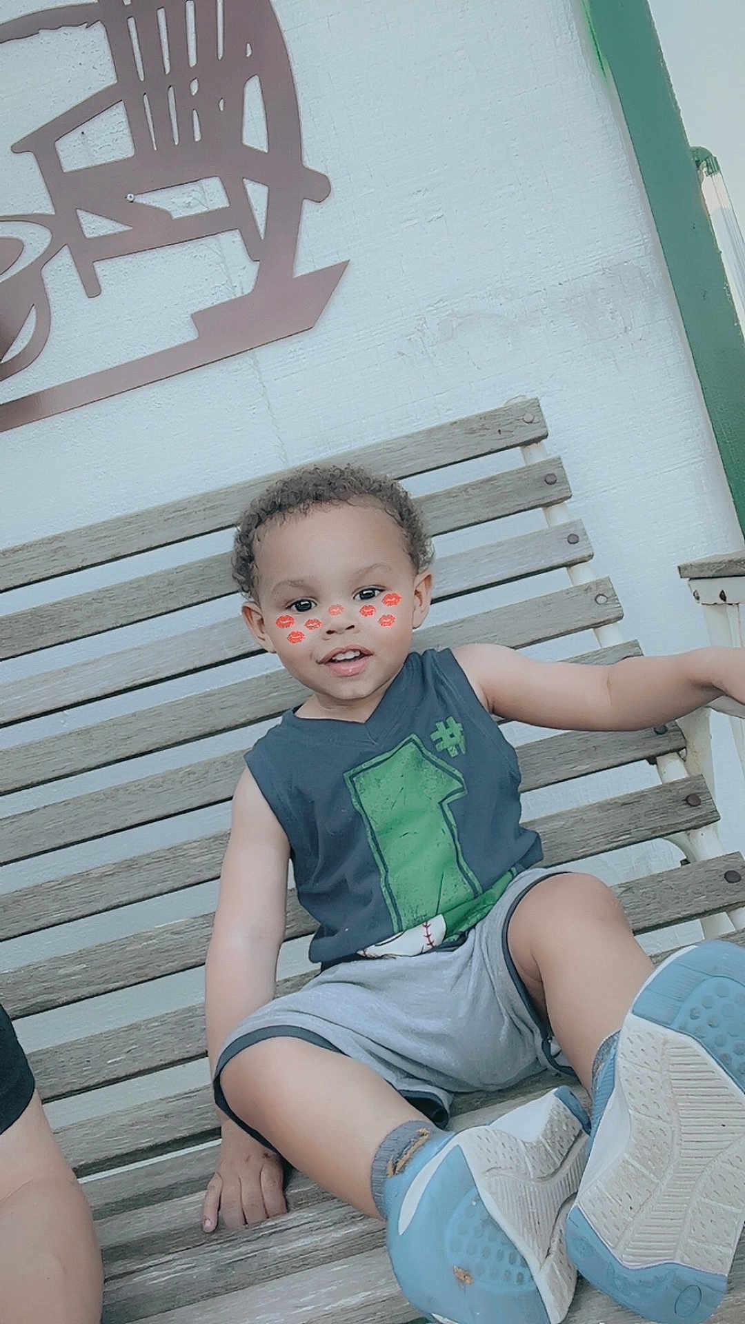 Ky Marshaun joined the competition — help win amazing prizes! child, toddler, smiling, sitting, bench, outdoor, curly_hair, sneakers, shorts, sleeveless_shirt, face_filter, kiss_marks, wooden_bench, relaxed, cute, playful, daytime, person, casual_clothing, happy