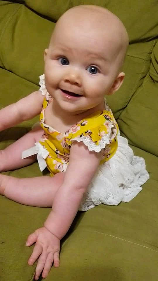 Pepper is registered to the contest to win money with this photo: baby, baby_products, baby_toddler_clothing, cheek, child, dress, eye, finger, fun, happy, human_body, infant_bodysuit, iris, joy, person, pink, sitting, skin, sleeve, smile