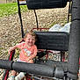 Emberly is registered to the contest to win money with this photo: toddler, child, smile, outdoor, go_kart, seat, grass, shoes, curly_hair, pink_shirt, sunny, nature, tree, petals, happy, vehicle, play, daytime, casual_clothing, park