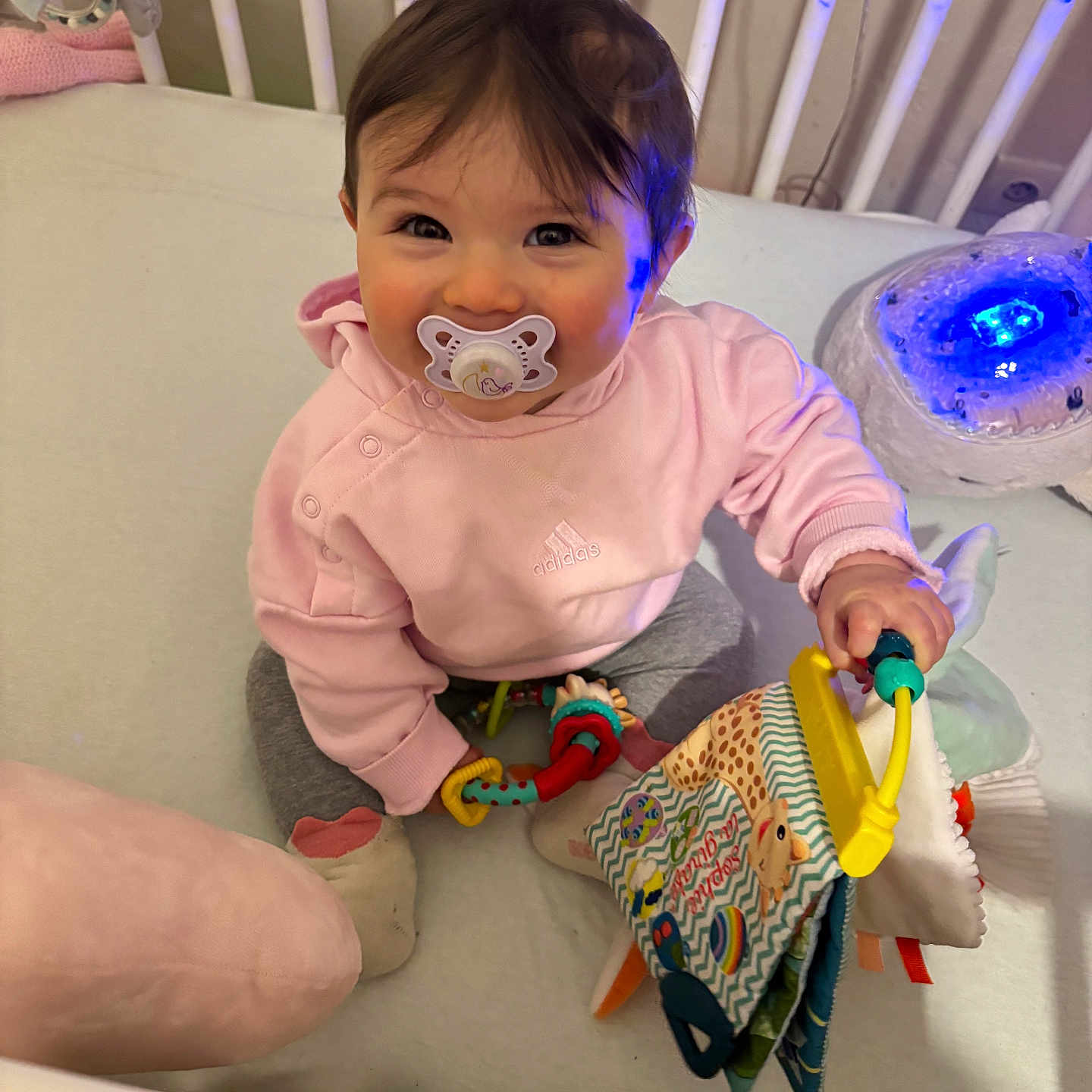Enéa a rejoint le concours — aidez-le/la à gagner de superbes lots ! baby, child, cozy, crib, cute, fabric_book, happy, home, indoor, infant, nightlight, pacifier, pink_hoodie, playtime, ring_toy, sitting, smiling, soft_lighting, toy, young_child