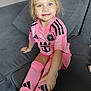 Théa participe au concours pour gagner de l'argent avec cette photo : child, girl, smiling, indoor, couch, pink_clothing, socks, blonde_hair, blue_eyes, sportswear, sitting, happy, portrait, casual, comfortable, cushion, home, person, young, cute