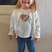 Théa participe au concours pour gagner de l'argent avec cette photo : child, girl, smiling, indoor, white_cardigan, blue_jeans, white_shoes, pigtails, blonde_hair, standing, floor_tiles, door, wallpaper, heart_design, casual_clothing, happy, portrait, full_body, cute, fashion