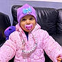 accessory, baby, beaded_clip, child, couch, cute, indoor, leather_couch, pacifier, pink, pink_jacket, plush_toy, portrait, purple, purple_hat, small_child, smiling, toddler, warm_clothes, winter_clothing