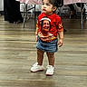 Kiki is registered to the contest to win money with this photo: child, girl, standing, red_shirt, denim_skirt, sneakers, portrait_print, indoor, wooden_floor, table, tablecloth, people, curious_expression, hair_tied, casual_clothing, party, flooring, legs, shoes, earrings