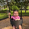 toddler, child, swing, playground, outdoor, smile, happy, grass, tree, fence, sunlight, pigtails, pink_shirt, park, wood_chips, person, baby, nature, daytime, fun