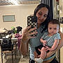 Brewer joined the competition — help win amazing prizes! woman, baby, mirror, selfie, indoor, casual_clothing, holding, smile, person, phone, shorts, socks, table, chair, rug, flower, decor, home, reflection, portrait