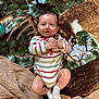 baby, infant, smiling, striped_onesie, blanket, nature_print, feet, socks, clothing, floor, wood_floor, happy, lying_down, child, person, indoor, cute, portrait, baby_toy, pacifier