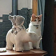Choupette participe au concours pour gagner de l'argent avec cette photo : animal, background, cat, ceramic_figurine, collar, cozy, curious, decor, feline, home, indoor, knitted_dolls, lighting, ornament, pet, polar_bear, statue, still_life, table, wooden_surface