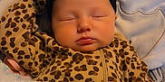 Aurora is registered to the contest to win money with this photo: baby, sleeping, infant, leopard_print, onesie, black_headband, bow, blanket, crocheted, pastel_colors, close_up, face, peaceful, cute, child, soft_lighting, cozy, resting, indoors, portrait