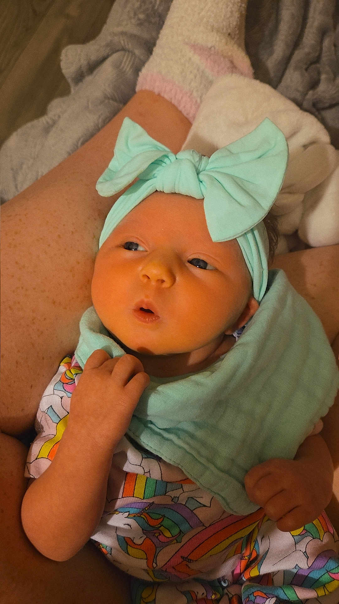 Aurora is registered to the contest to win money with this photo: baby, infant, headband, bow, clothing, unicorn, colorful, blanket, legs, socks, person, hand, skin, cute, lying, fabric, pattern, indoors, cozy, soft