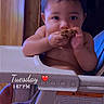 Jeremiah is registered to the contest to win money with this photo: baby, high_chair, cookie, indoor, child, cute, eating, food, hands, face, foot, furniture, wood, table, time_stamp, heart_emoji, skin, expression, curious, portrait
