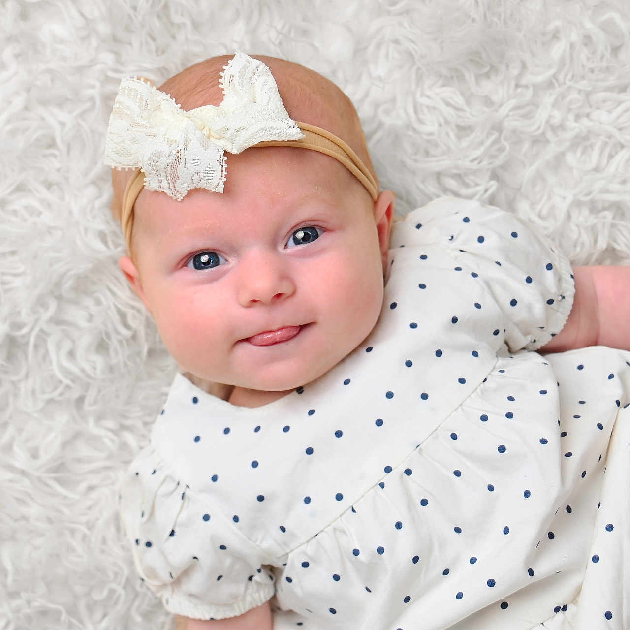 Iris joined the competition — help win amazing prizes! adorable, baby, blanket, blue_eyes, child, closeup, cute, headband, indoor, infant, lace, lying_down, person, polka_dot, portrait, skin, smiling, soft_texture, tongue_out, white_clothing