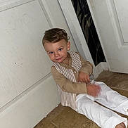 Kayden participe au concours pour gagner de l'argent avec cette photo : barefoot, boy, casual, child, clothing, cute, door, face, floor, hair, indoor, pants, person, portrait, sitting, smile, tile_floor, toddler, vest, young_child