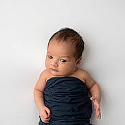 Lemon is registered to the contest to win money with this photo: baby, infant, newborn, wrapped, blue_cloth, lying_down, white_background, curious, face, skin, head, eyes, hand, arm, portrait, cute, child, alone, indoors, soft_light