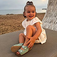 Louise participe au concours pour gagner de l'argent avec cette photo : toddler, child, beach, sand, sea, smile, sitting, sandal, white_dress, hair_bow, outdoor, sunset, cloudy_sky, happy, portrait, lounge_chair, footwear, cute, playful, nature