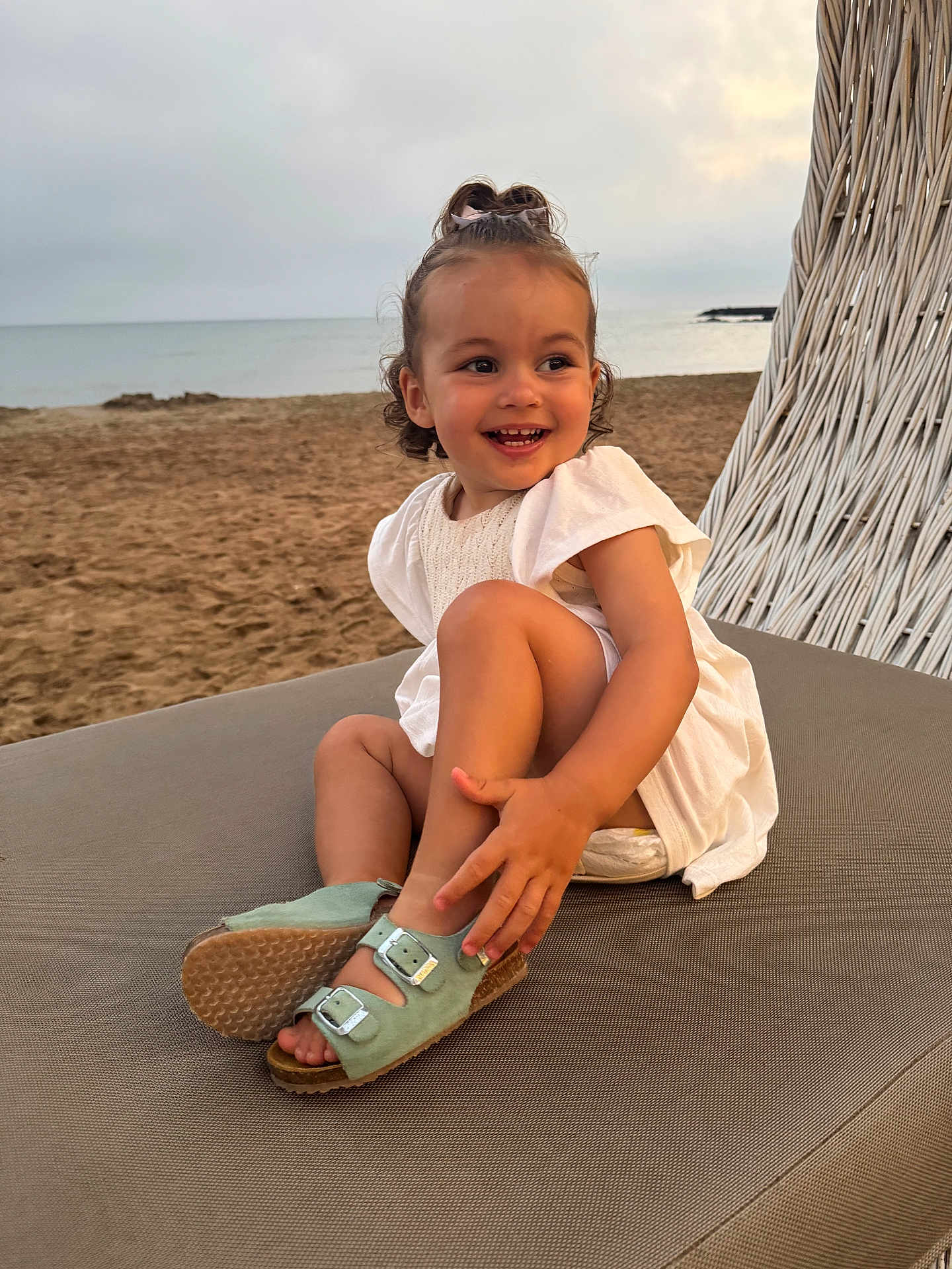 Louise participe au concours pour gagner de l'argent avec cette photo : toddler, child, beach, sand, sea, smile, sitting, sandal, white_dress, hair_bow, outdoor, sunset, cloudy_sky, happy, portrait, lounge_chair, footwear, cute, playful, nature