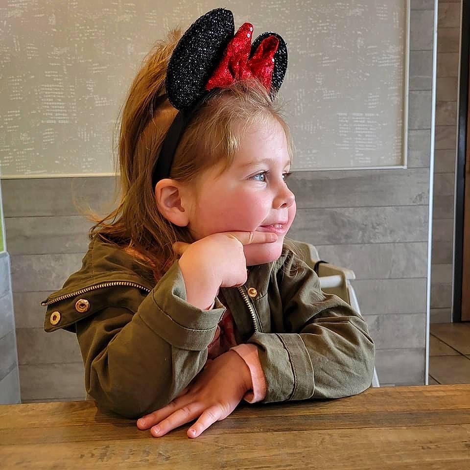 Elliot is registered to the contest to win money with this photo: brown_hair, cheek, child, ear, eyelash, fashion_accessory, flooring, happy, hardwood, headband, headpiece, jewellery, lip, person, portrait_photography, sitting, sleeve, table, toddler, varnish