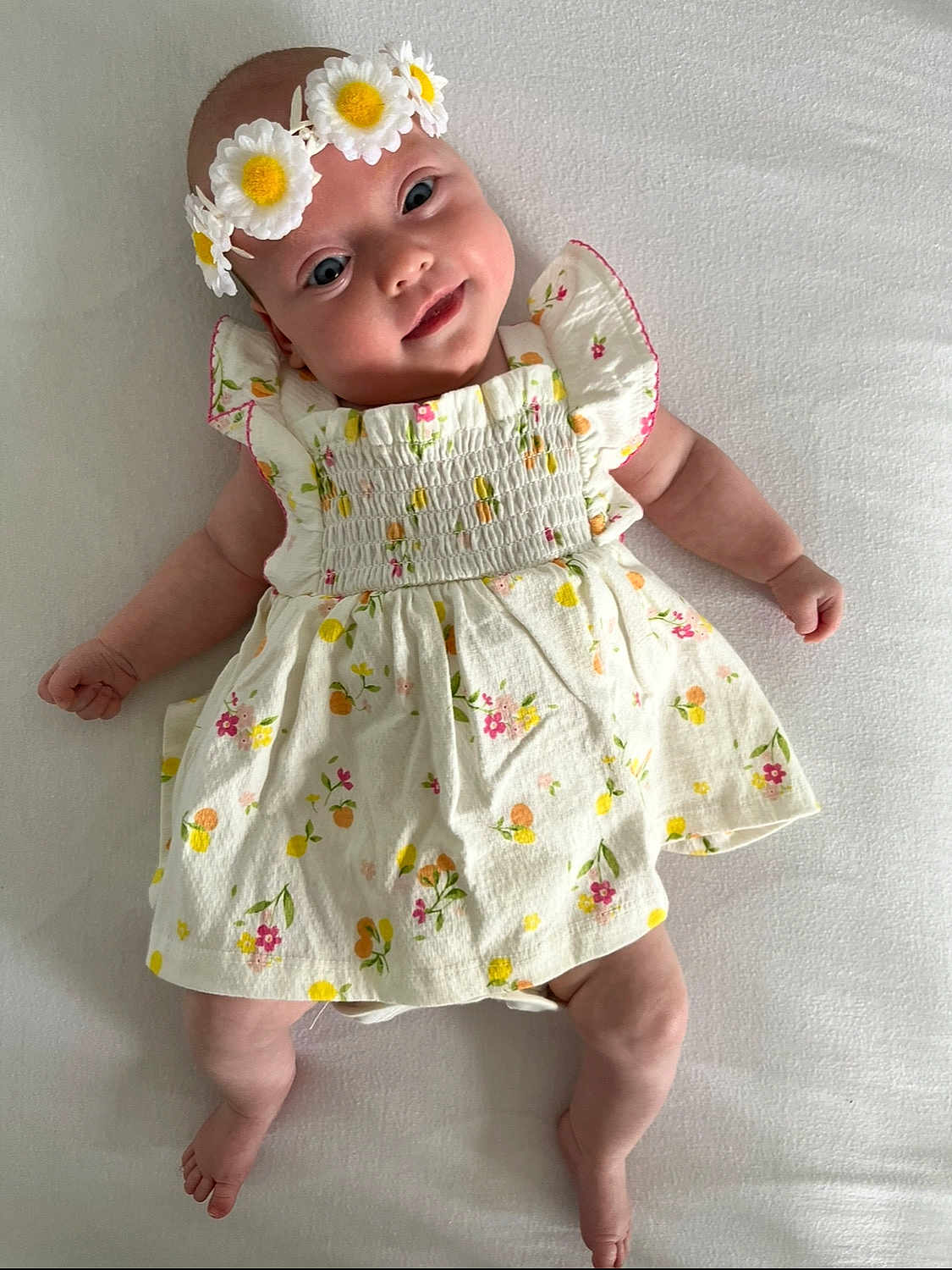 Lexi is registered to the contest to win money with this photo: baby, child, flower_crown, dress, floral_pattern, smile, lying_down, white_background, cute, infant, happy, skin, headband, small_hands, small_feet, portrait, closeup, indoors, person, adorable