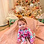 baby, child, infant, pajamas, pink_blanket, christmas_tree, ornaments, lights, holiday, indoor, curious, sitting, decorations, floor, present, gift_bags, festive, cute, face, person