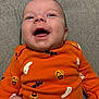 baby, child, infant, smiling, orange_clothing, onesie, halloween, ghost, pumpkin, bat, happy, face, head, person, cute, lying_down, gray_background, festive, joyful, portrait