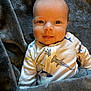 Asher is registered to the contest to win money with this photo: baby, infant, blanket, onesie, shark_pattern, face, smile, eyes, cute, cozy, soft_texture, child, portrait, indoor, clothing, person, head, expression, lying_down, warm