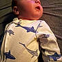 Asher is registered to the contest to win money with this photo: baby, infant, child, onesie, shark_print, turtle_print, clothing, sleepwear, laying_down, soft_lighting, face, head, cute, young_child, indoors, portrait, fabric, warm_light, expression, resting