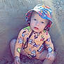 beach, bucket_hat, child, colorful_clothing, cute, expression, eyes, face, hands, nature, outdoor, play, recreation, sand, sitting, summer, sunlight, swimsuit, toddler, vacation