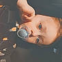child, baby, pacifier, face, hand, close_up, infant, young_child, portrait, indoor, soft_lighting, baby_clothes, expression, cute, relaxed, car_seat, seatbelt, skin, head, eyes