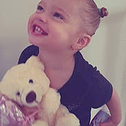 Oceanna joined the competition — help win amazing prizes! black_shirt, child, cute, drink, earrings, floor, hair_tied, happy, holding, indoors, portrait, small_person, smiling, socks, standing, strawberry, teddy_bear, toy, wall, wooden_floor