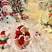 Amanda is registered to the contest to win money with this photo: baby, sleeping, santa_claus_costume, christmas, holiday, snowman, elf_doll, christmas_tree, gifts, lantern, decorations, festive, white_cotton, soft_cushion, red_hat, red_clothing, holiday_scene, cute, indoors, winter_theme