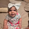 Gemma joined the competition — help win amazing prizes! baby, child, headband, bow, smile, face, eyes, clothing, floral, overalls, cute, portrait, infant, sitting, indoors, skin, hand, person, soft_light, closeup
