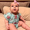 baby, infant, child, romper, floral_pattern, headband, pink_bow, sitting, bed, pillow, skin, cute, indoors, portrait, chubby, curious, young, person, soft_lighting, comfortable