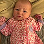 apparel, baby, blanket, child, cozy, cute, face, giraffe_pattern, hands, indoor, infant, lying_down, newborn, onesie, person, pink, portrait, relaxed, sleepwear, soft